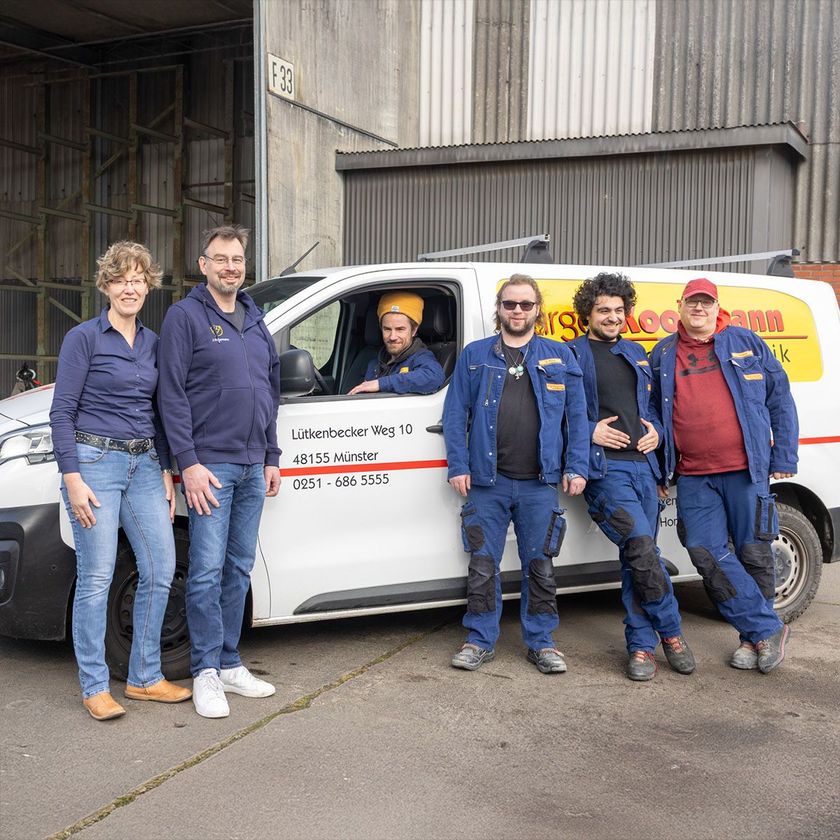 Eine Gruppe von Menschen steht vor einem Lieferwagen.