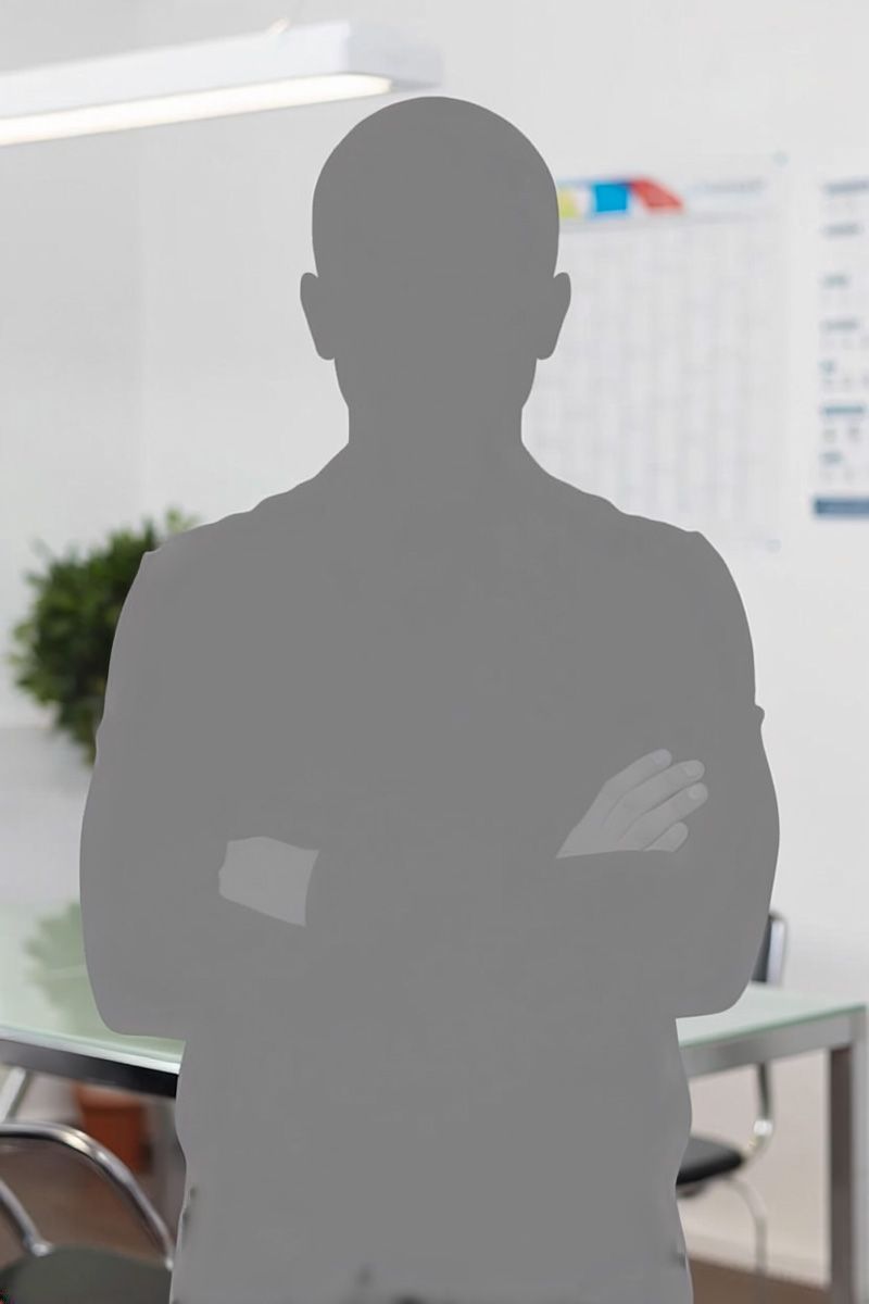 Eine Person mit verschränkten Armen steht als Silhouette in einem Büro; im Hintergrund sind ein Schreibtisch und eine Tafel zu sehen.