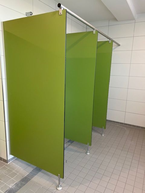 Eine Reihe grüner Trennwände in einem Badezimmer.