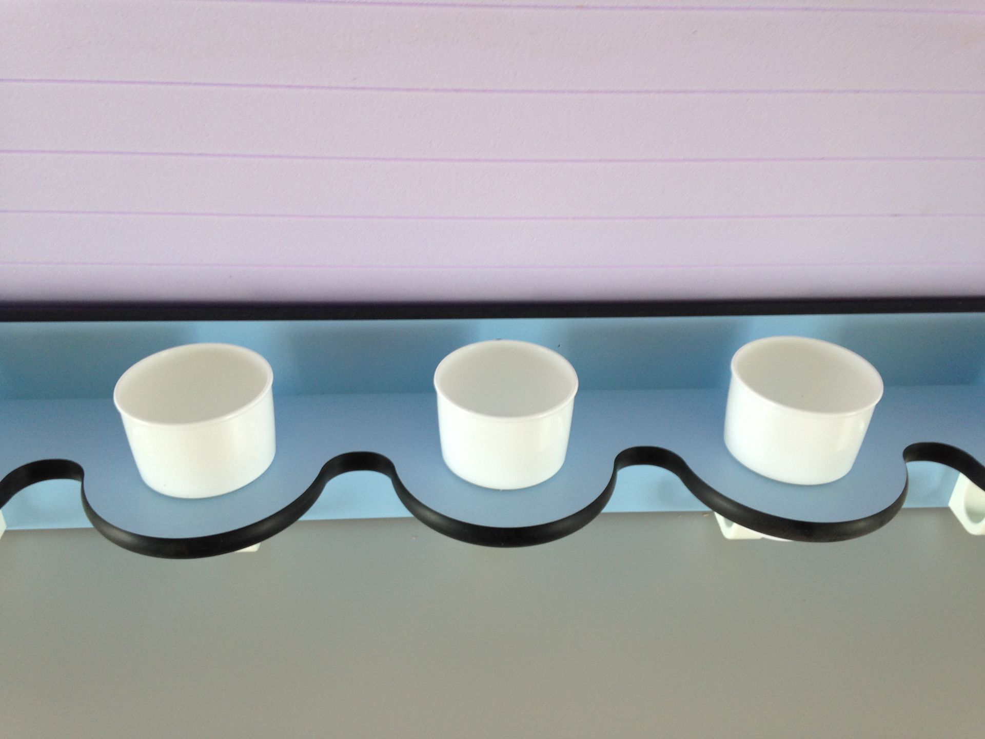 Drei weiße Tassen stehen auf einem blauen Regal