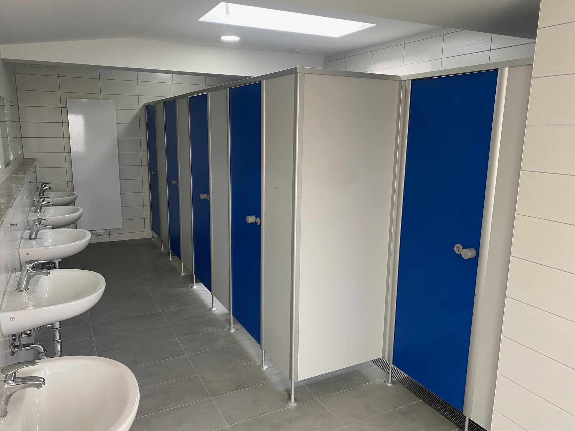 Ein Badezimmer mit blauen und weißen Kabinen und Waschbecken.