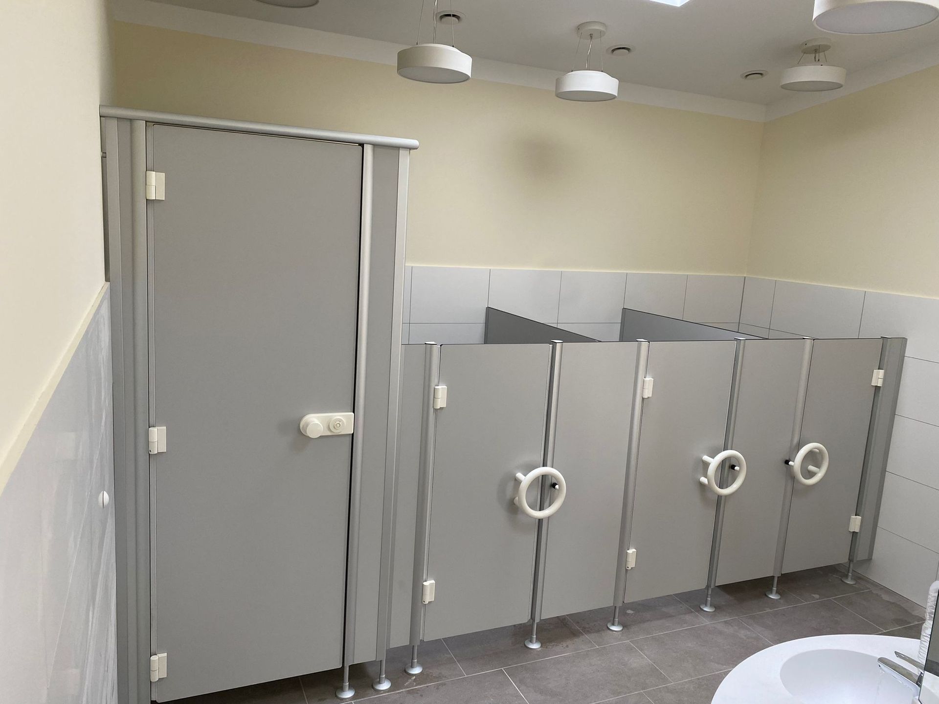 Ein Badezimmer mit Waschbecken und Toilettenkabinen.