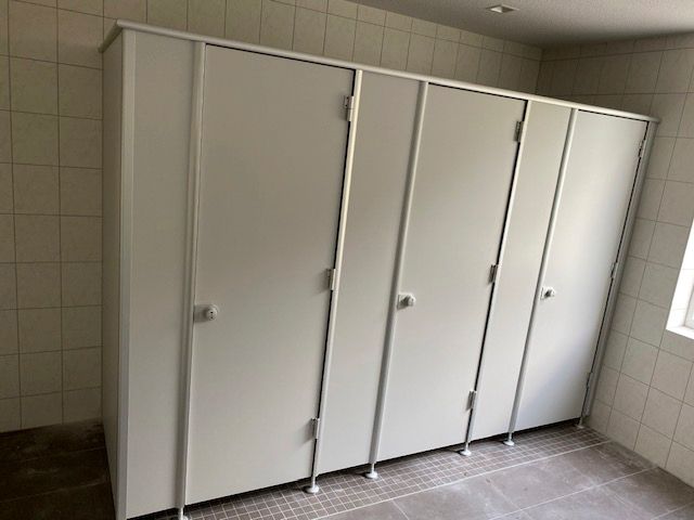 Eine Reihe weißer Toilettenkabinen in einem Badezimmer.