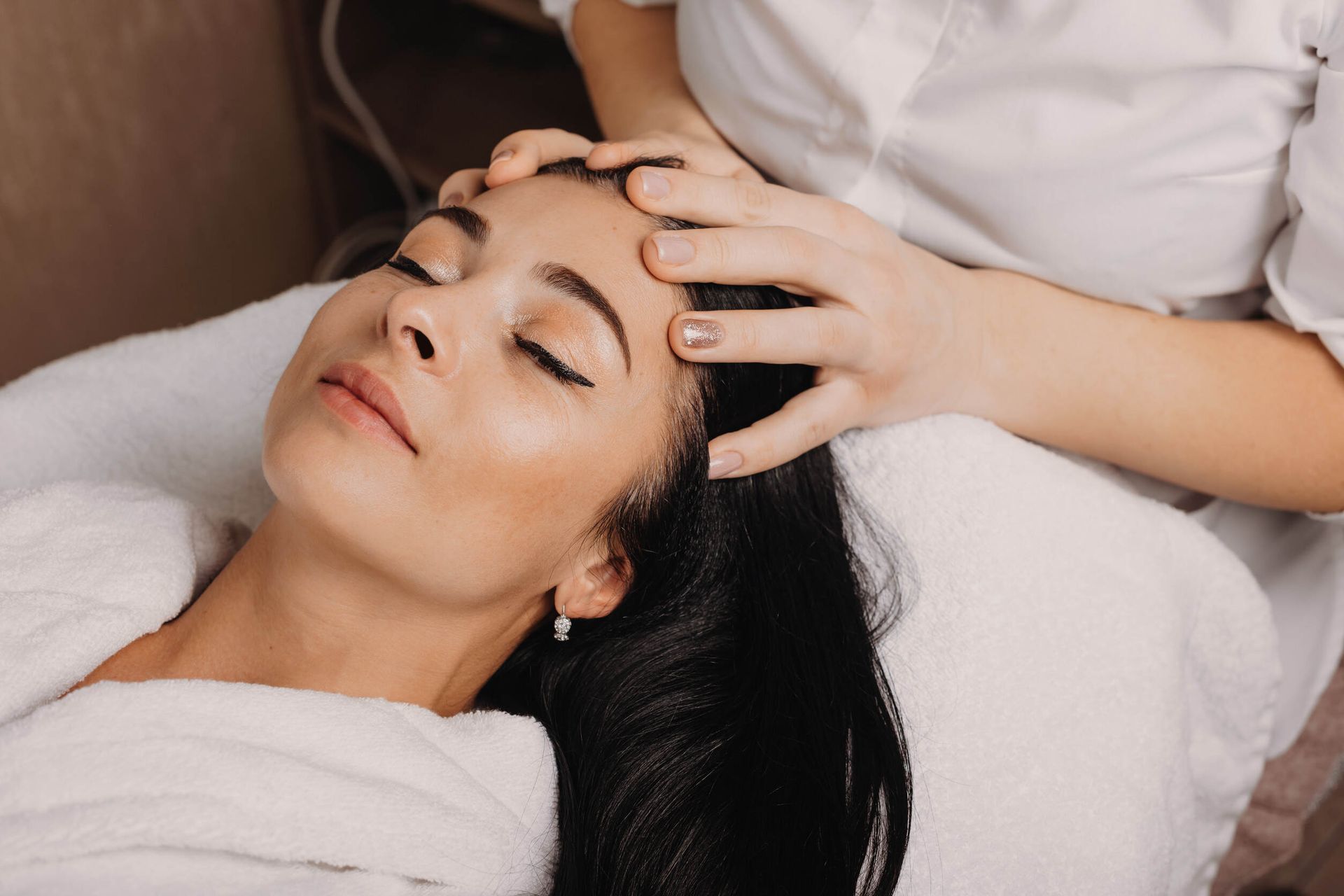 Una mujer está recibiendo un masaje de cabeza en un spa.
