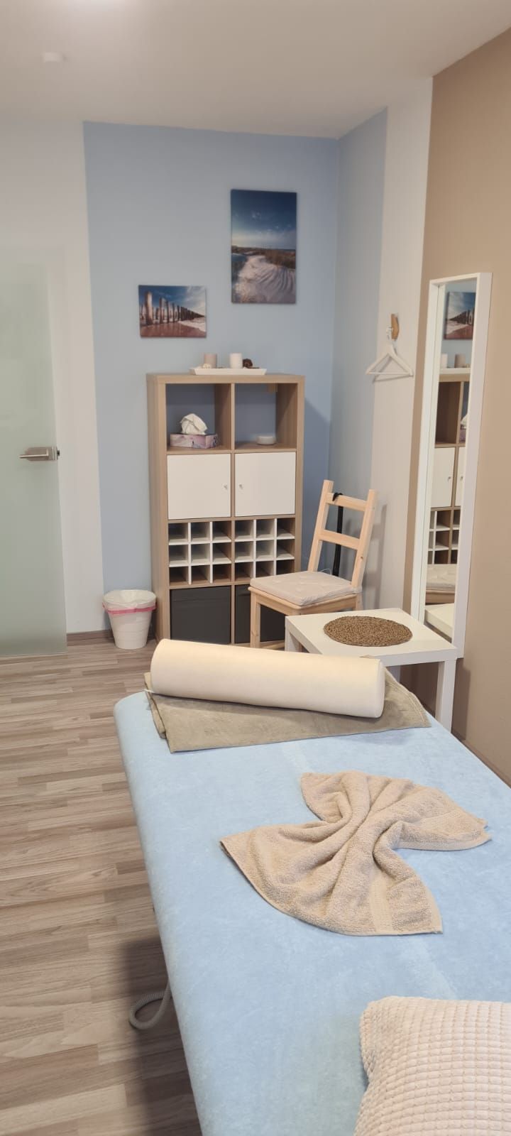 Ein Zimmer mit einem Bett, Stühlen, einem Spiegel und einem Regal.