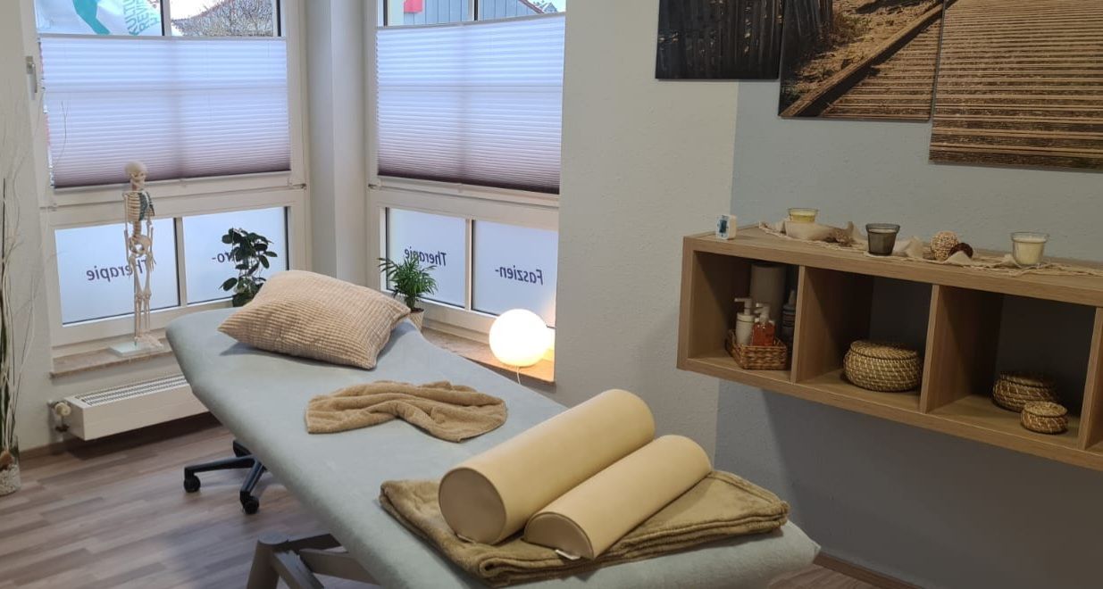 Eine Massageliege in einem Raum mit vielen Fenstern.