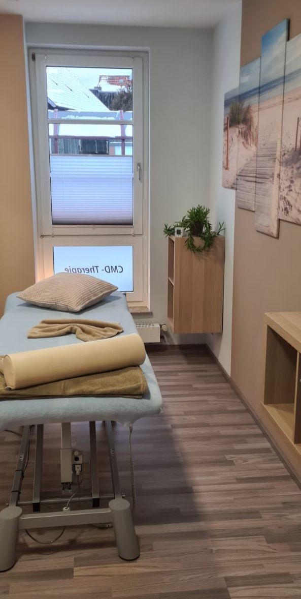 Ein Raum mit einem Massagetisch und einem Fenster.