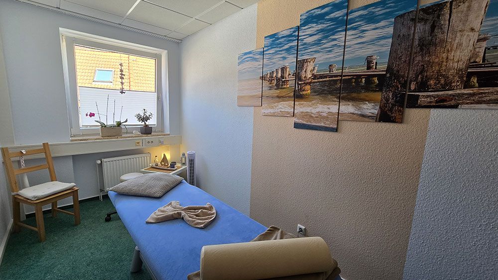 Ein Zimmer mit einem Bett, einem Stuhl und Bildern an den Wänden.