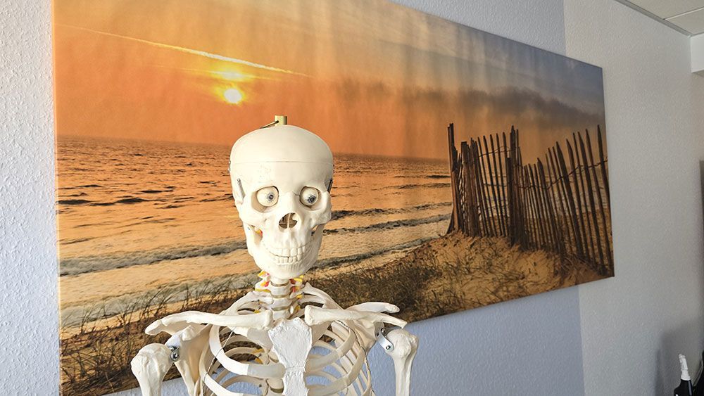 Ein Skelett steht vor einem Gemälde eines Strandes.