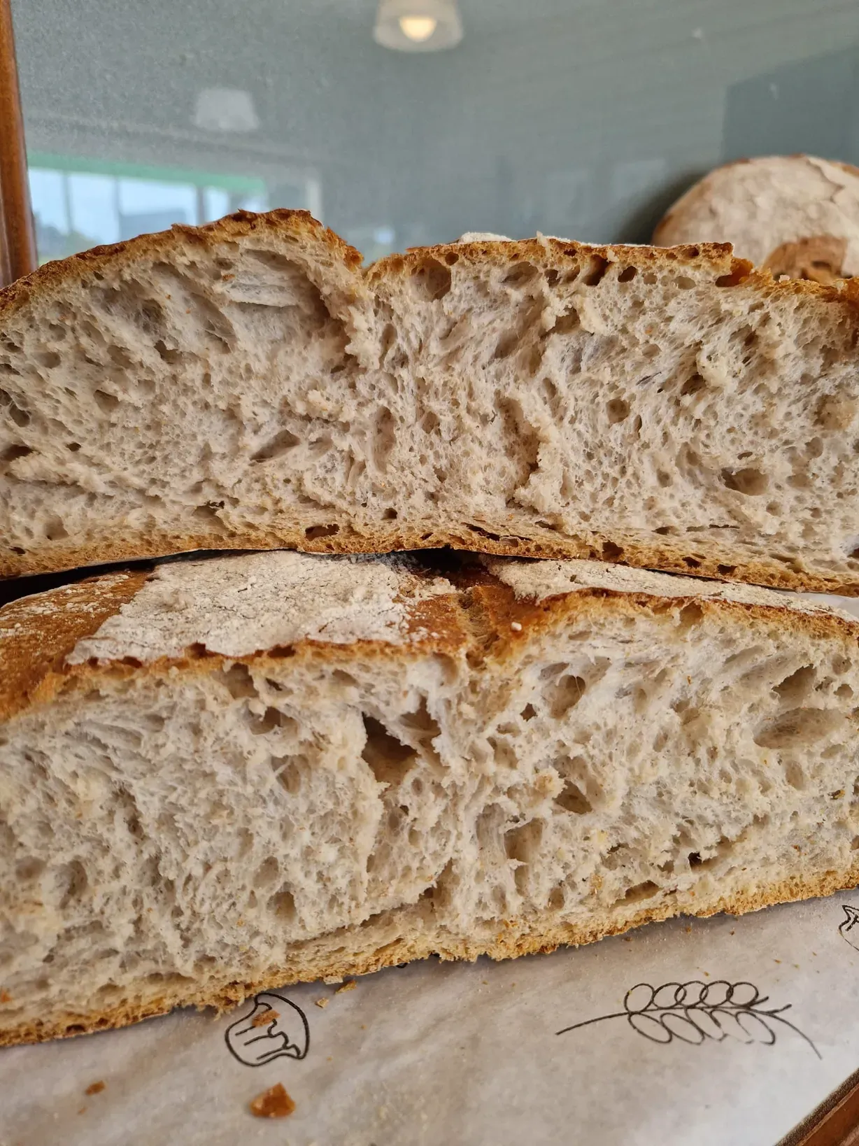 Pan de masa madre rebanado, con miga aireada. La corteza está dorada, el interior es beige con grandes agujeros .