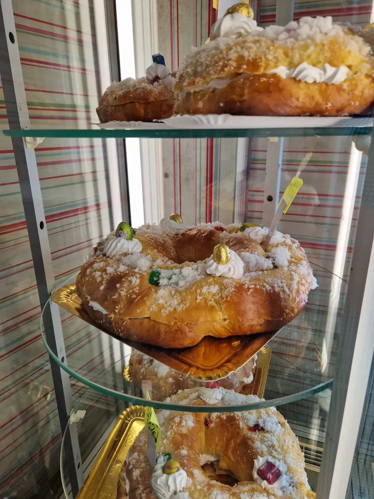 Vitrina con diversos pasteles en forma de roscón, decorados con crema, fruta confitada y cristales de azúcar.