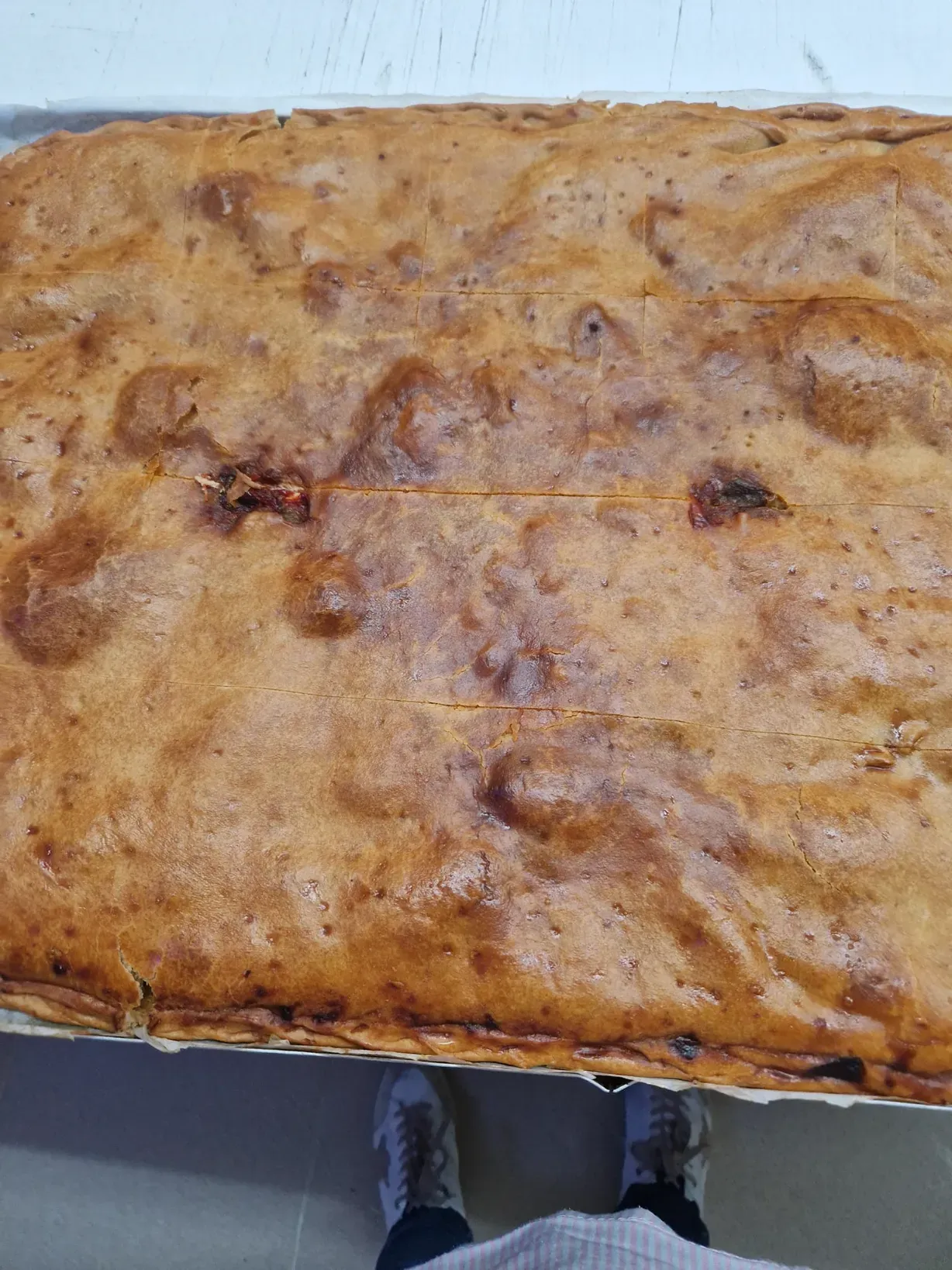 Pan grande rectangular horneado en sartén, con superficie dorada y líneas de corte.