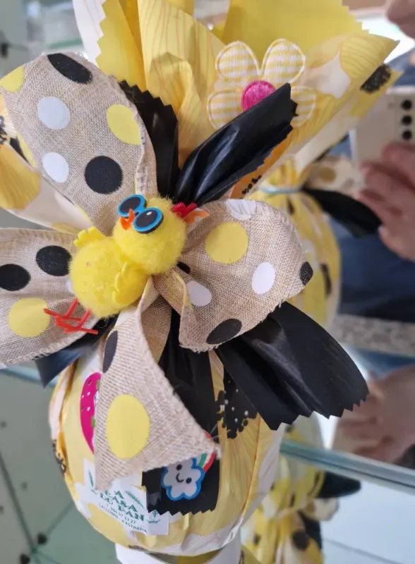 Huevo de Pascua envuelto en tela amarilla con lazo de lunares y decoración de pollito.