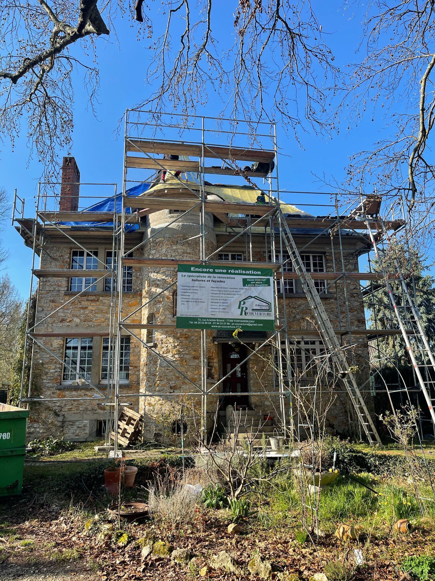 Maison ancienne en rénovation avec échafaudage et bâche sur le toit
