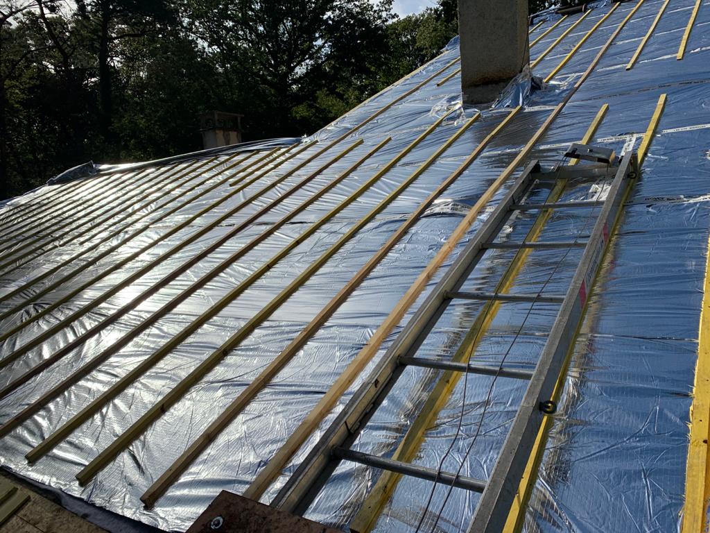 Toit en rénovation avec sous-couche réfléchissante et lattage en bois posé pour la future couverture