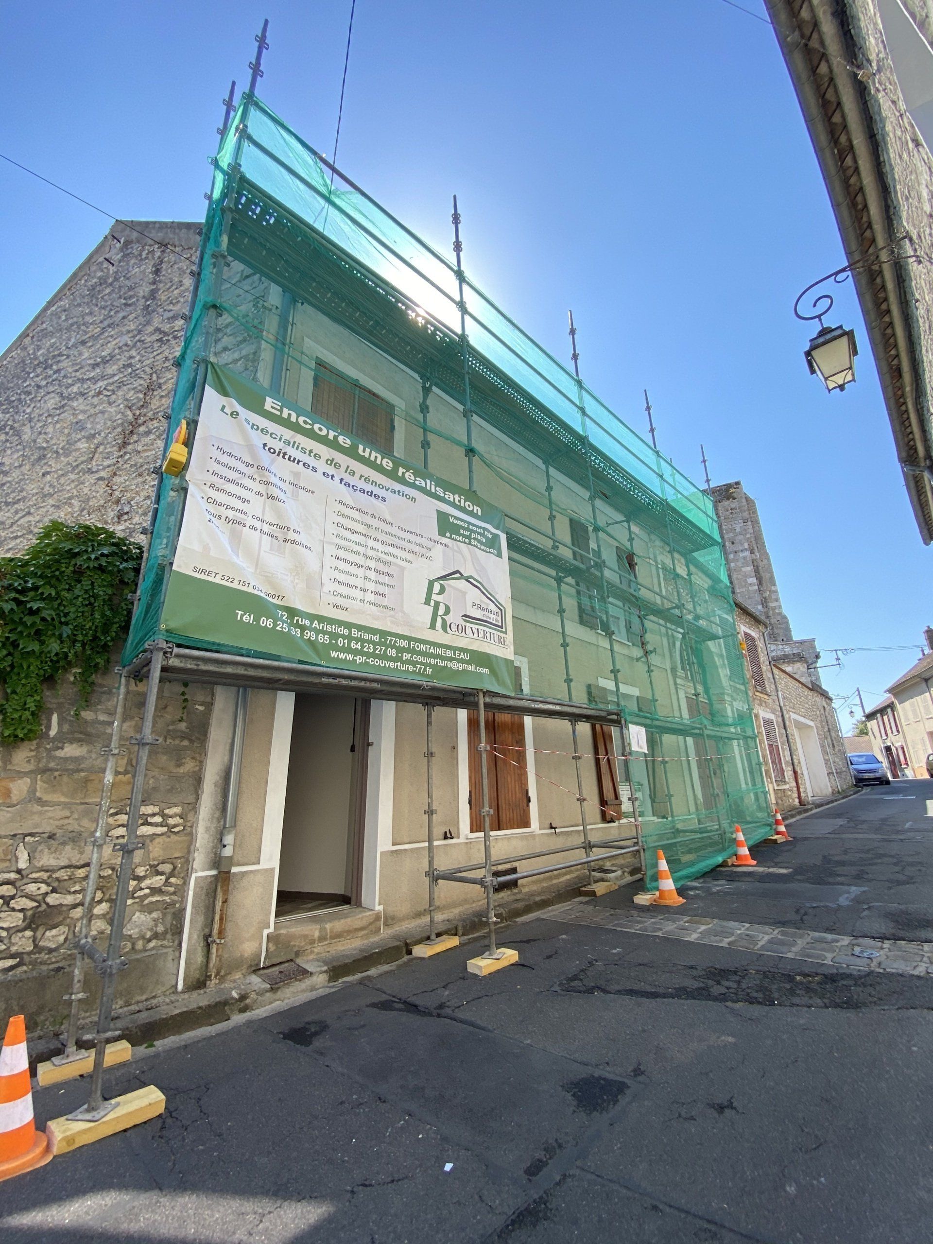 Façade d'un bâtiment en rénovation avec panneau d'informations et filet de protection