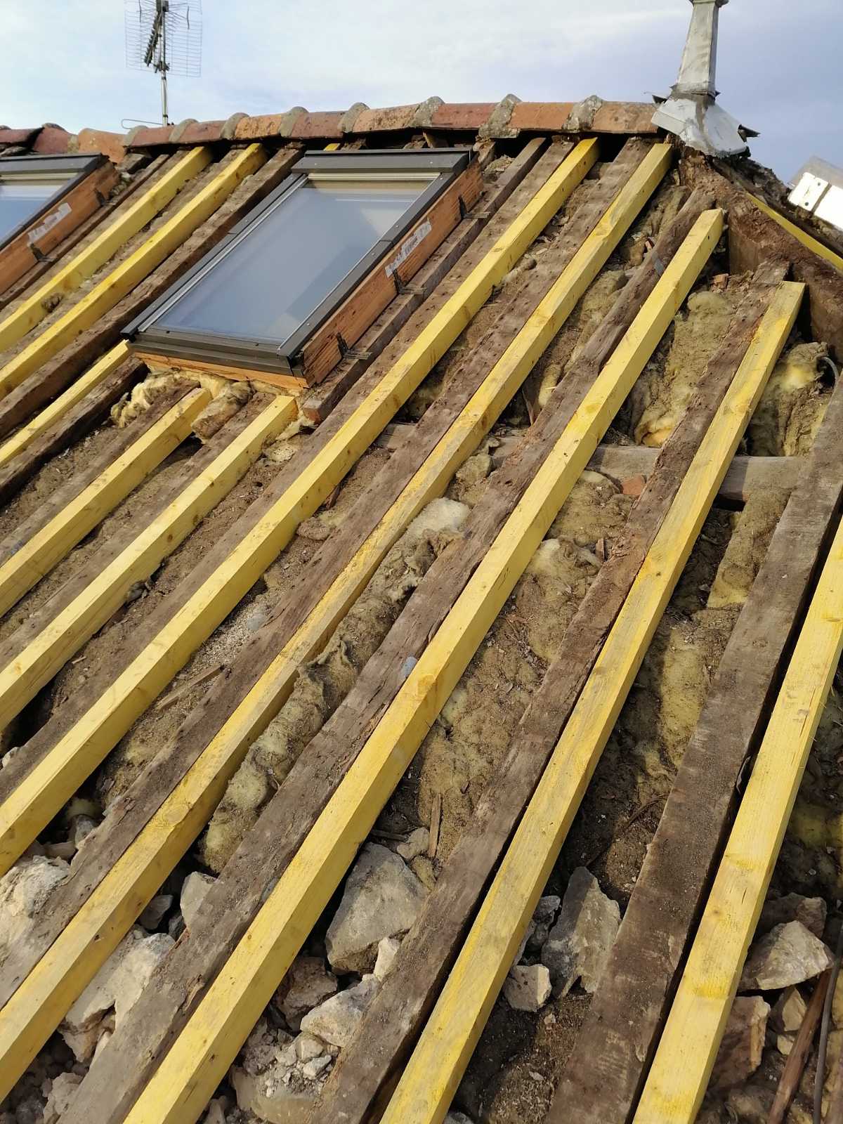 Détail d'isolation et de lattage en bois usé par le temps avant rénovation du toit