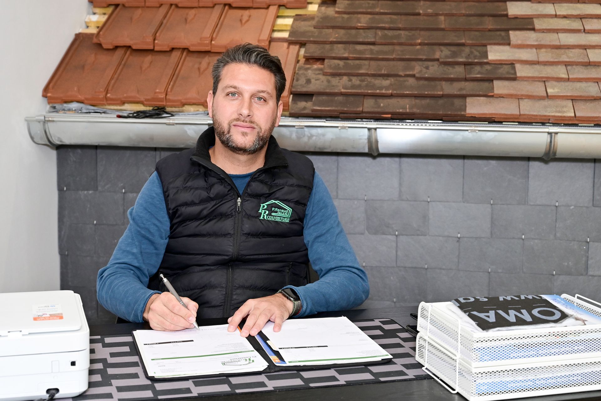 Artisan assis au bureau regardant l'objectif et signant un document dans le showroom de PR Couverture