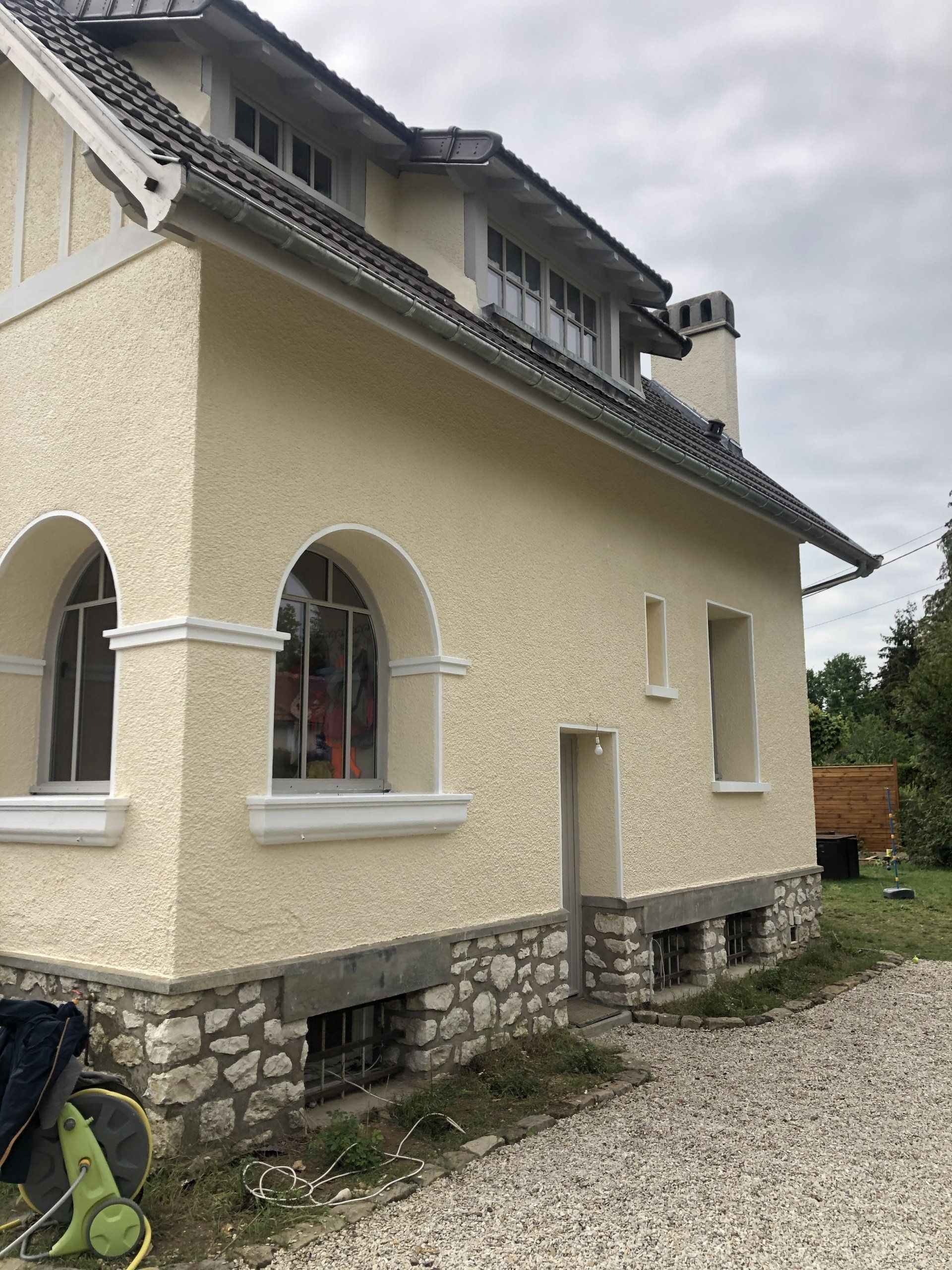 Maison en crépi beige avec fenêtres en arc et toit en tuile