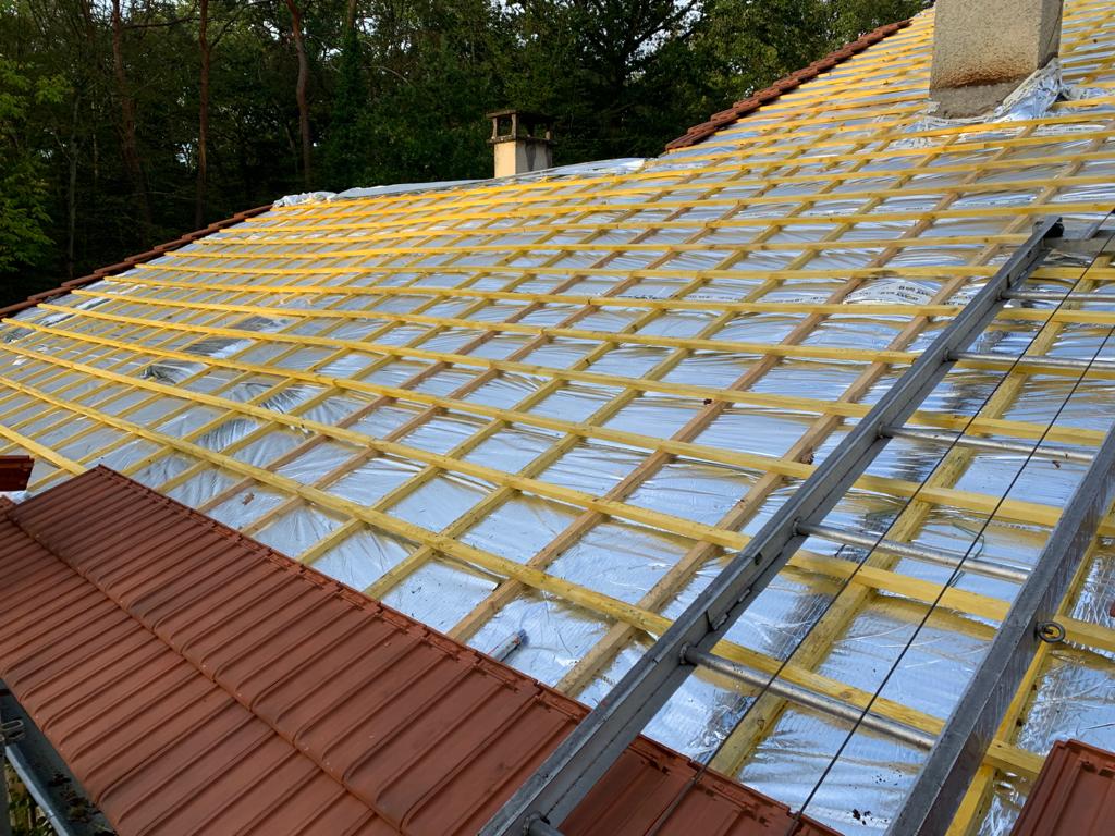 Toit en chantier avec isolation posée sous le lattage en bois et début de la pose de la couverture finale