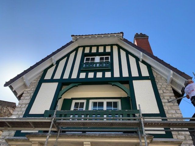 Maison à colombage avec façade blanche et verte et toit en ardoise