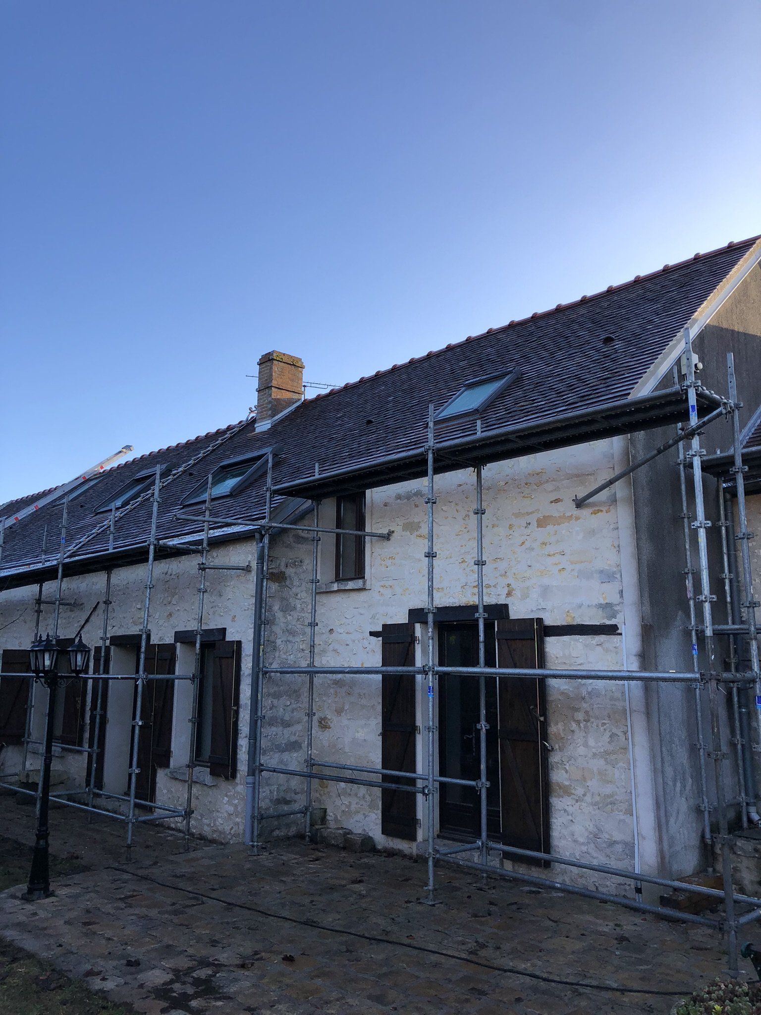 Maison ancienne avec échafaudage sur toute la longueur du toit en rénovation