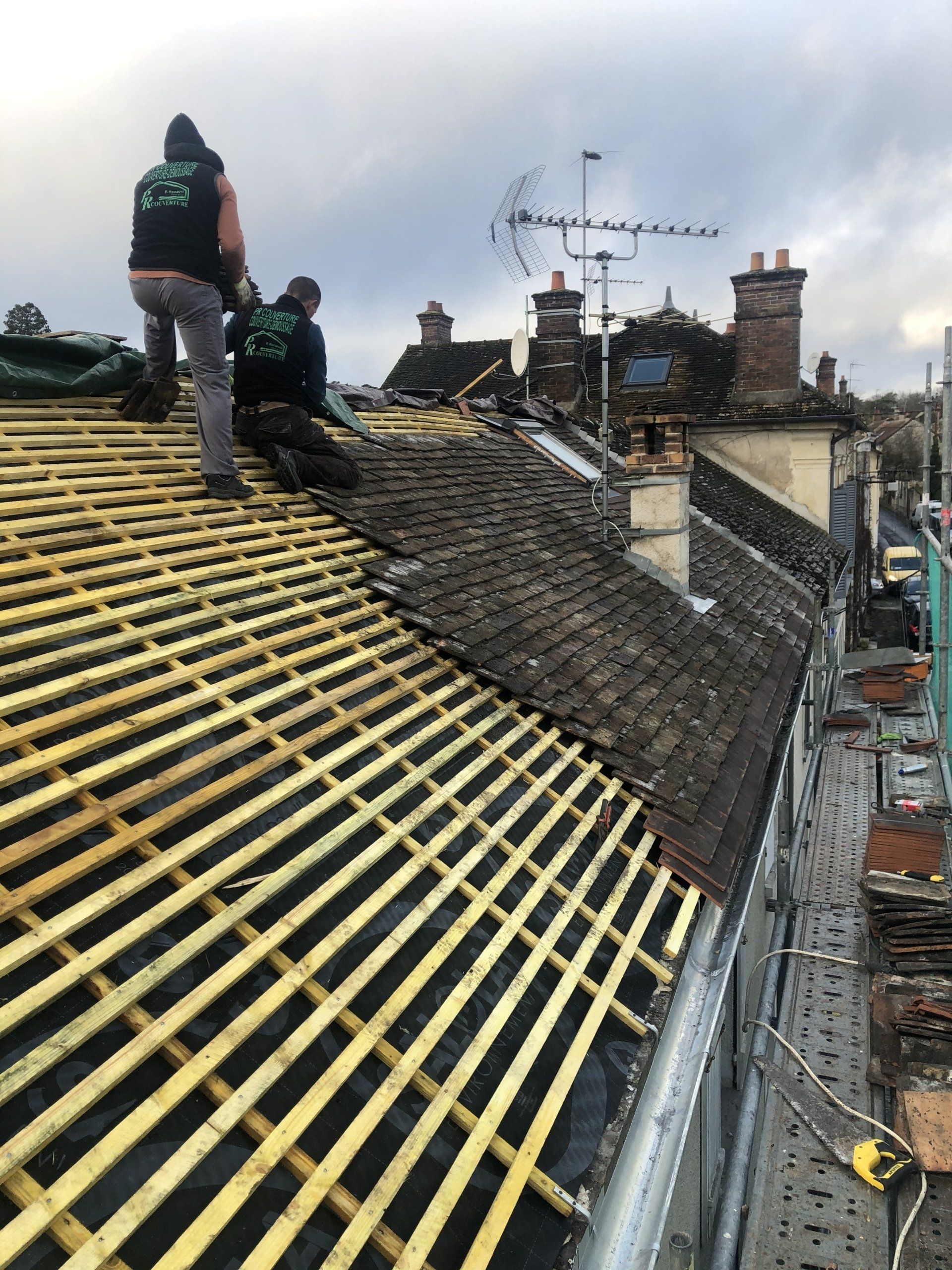 Toit en rénovation avec lattage en bois et tuiles partiellement posées