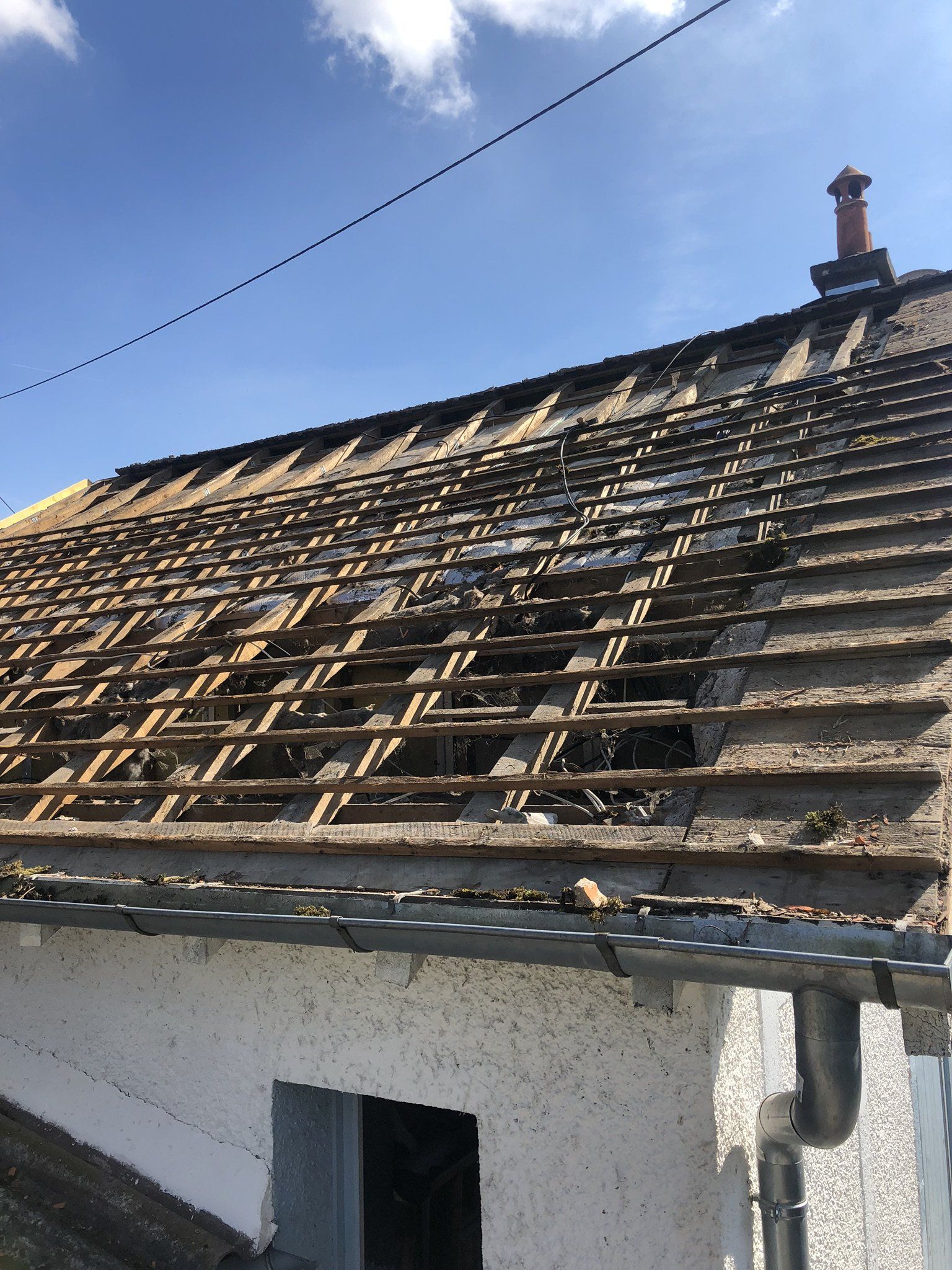 Toit ancien délabré en cours de rénovation avec lattage en bois visible