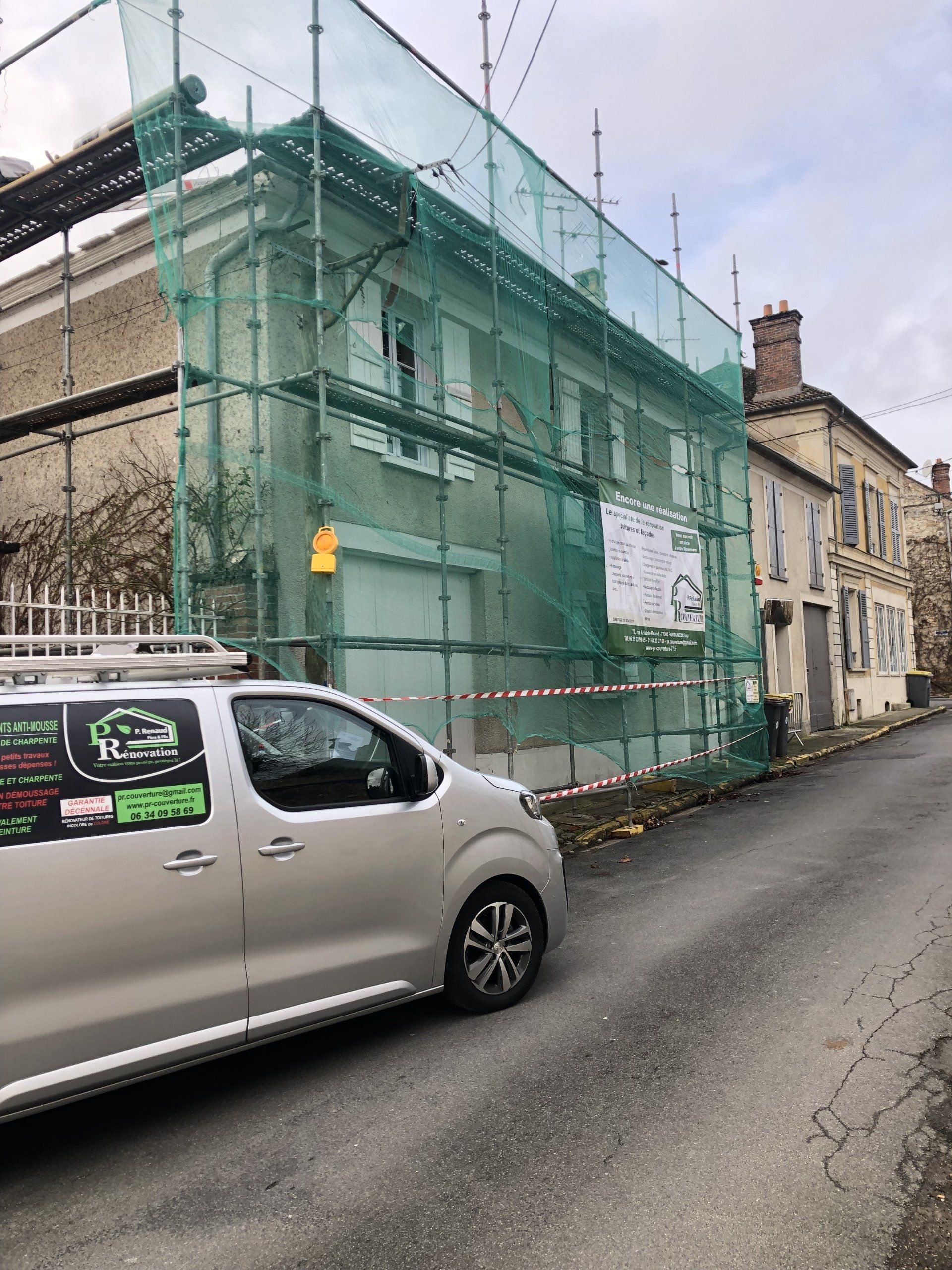 Bâtiment en rénovation par l'entreprise PR Couverture recouvert d'un filet de protection avec véhicule utilitaire garé devant