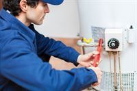 Ein Mann repariert einen Warmwasserbereiter mit einem Schraubenschlüssel.