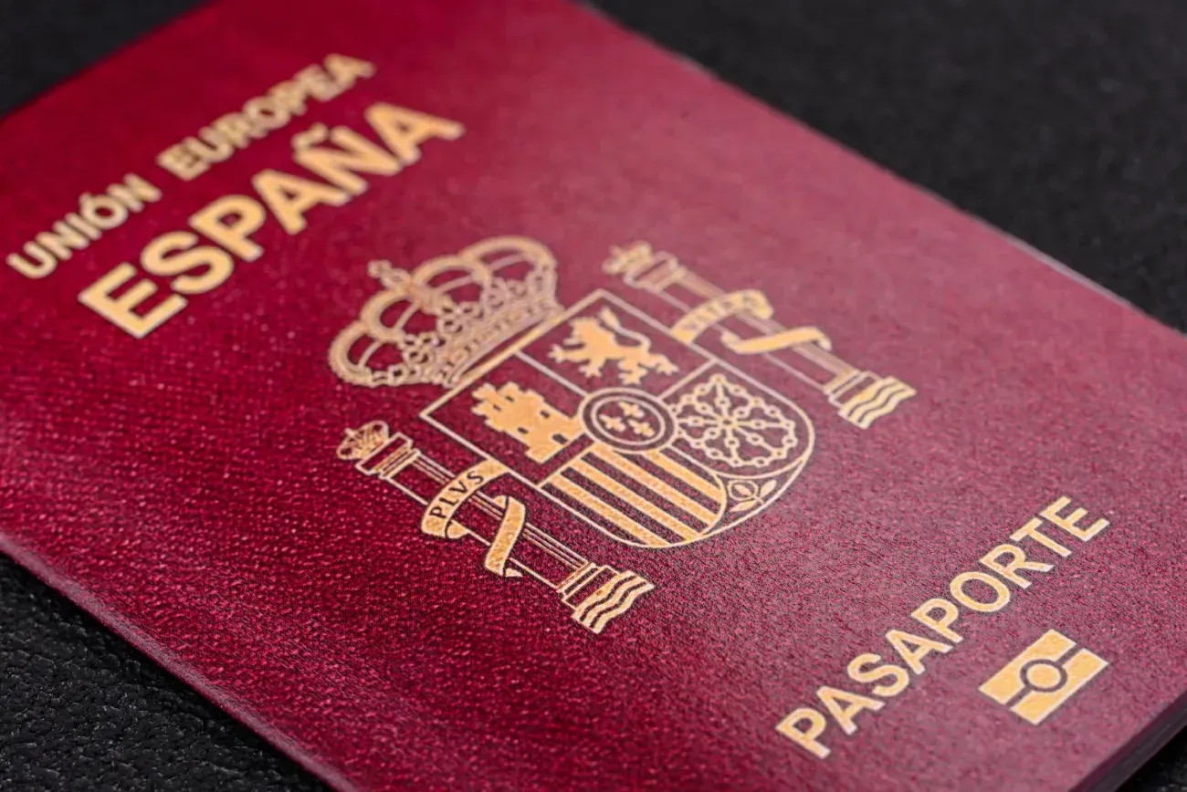 Un primer plano de un pasaporte español sobre una superficie negra.