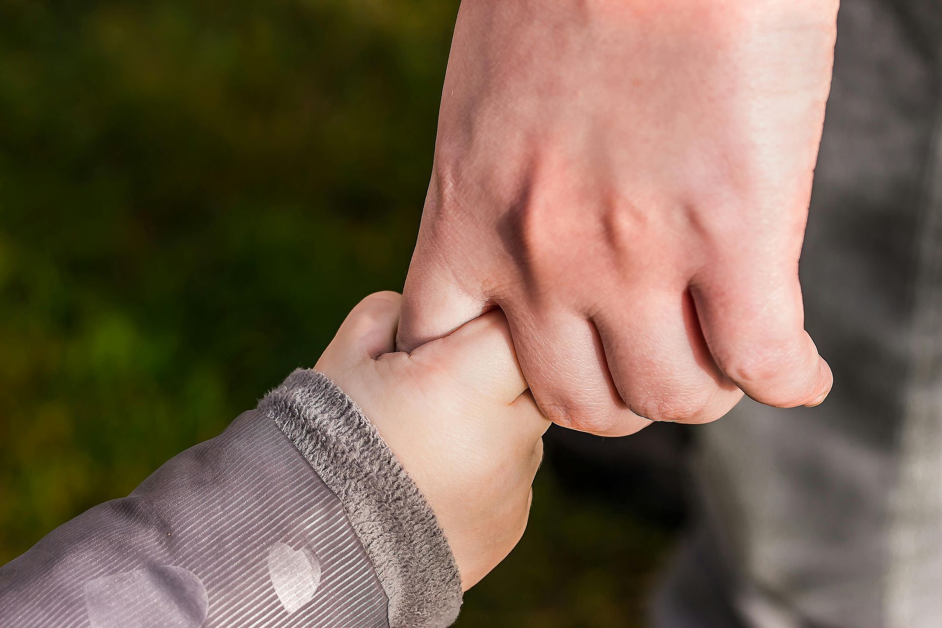 Un primer plano de una persona sosteniendo la mano de un niño.