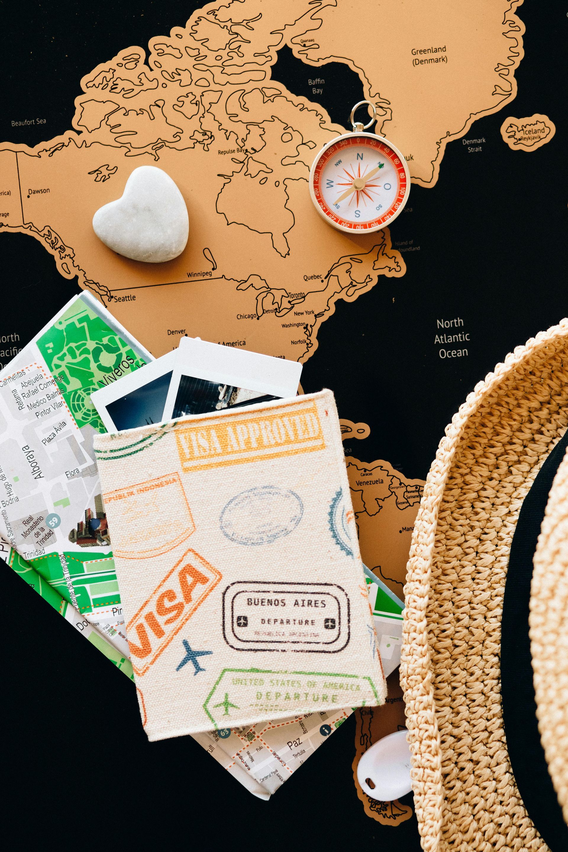 Un pasaporte está encima de un mapa al lado de una brújula y un sombrero.