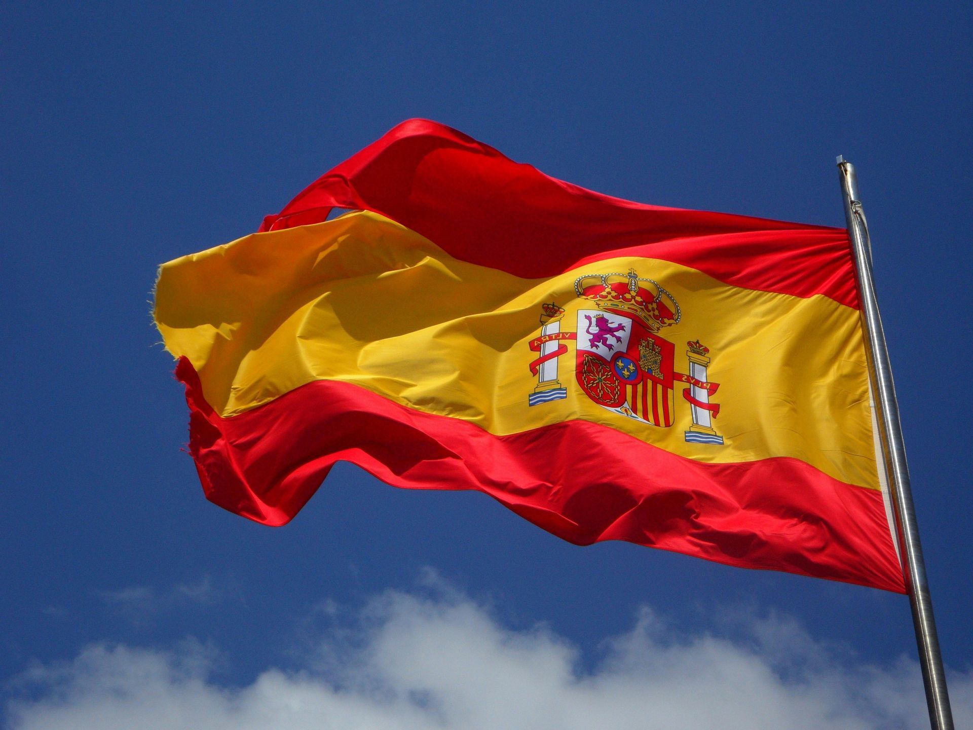 Una bandera española ondea en el viento contra un cielo azul