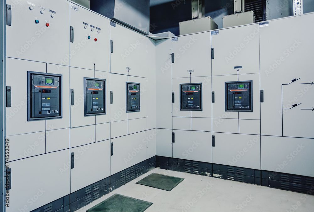 Weisse industrielle elektrische Schaltschränke säumen eine Wand in einem Hauswirtschaftsraum