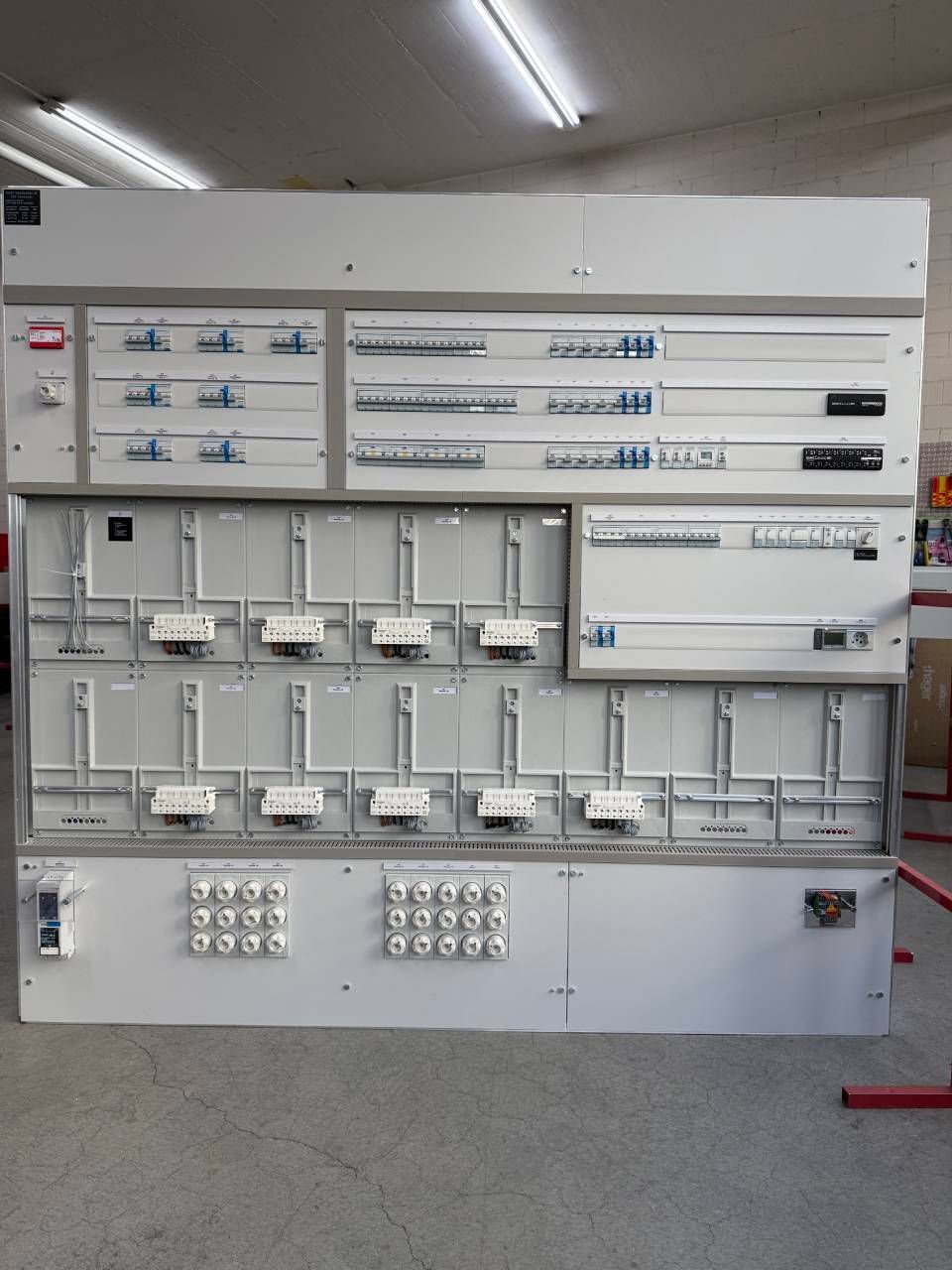An der Wand montierter elektrischer Schaltschrank mit Verkabelung, Schaltern und Schaltungskomponenten in einer Werkstatt.
