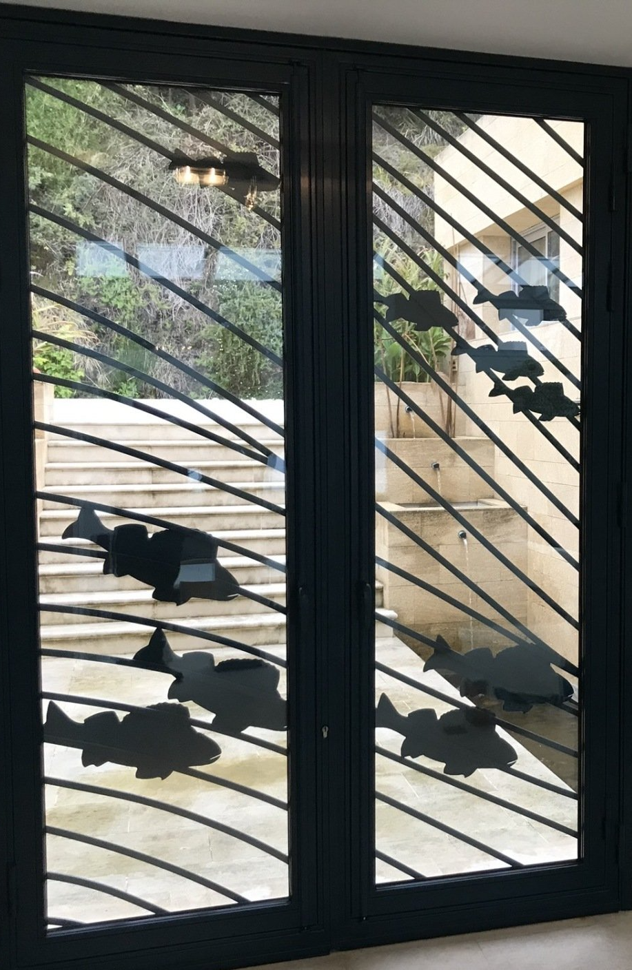 Porte d'entrée en fer noir avec dessins de poissons