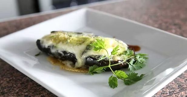 Plat gratiné au fromage fondu et aux herbes, servi dans une assiette carrée blanche.