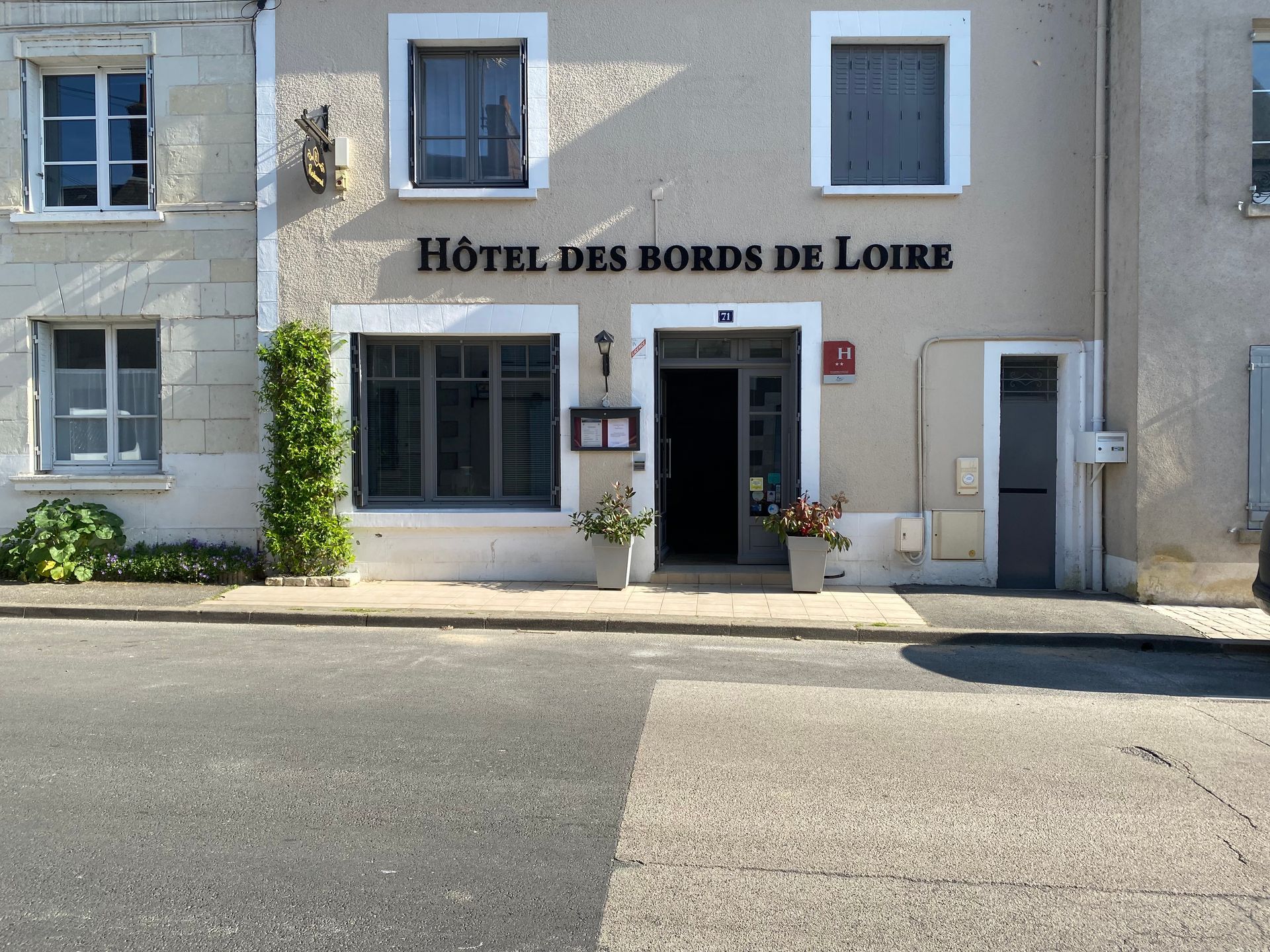 Façade de l'HÔTEL DES BORDS DE LOIRE avec murs crème, volets bleus.