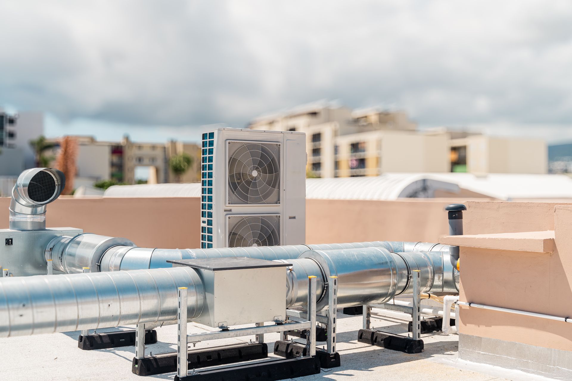 Unità HVAC con canalizzazione sul tetto, possibilmente in un contesto urbano. Giornata di sole.