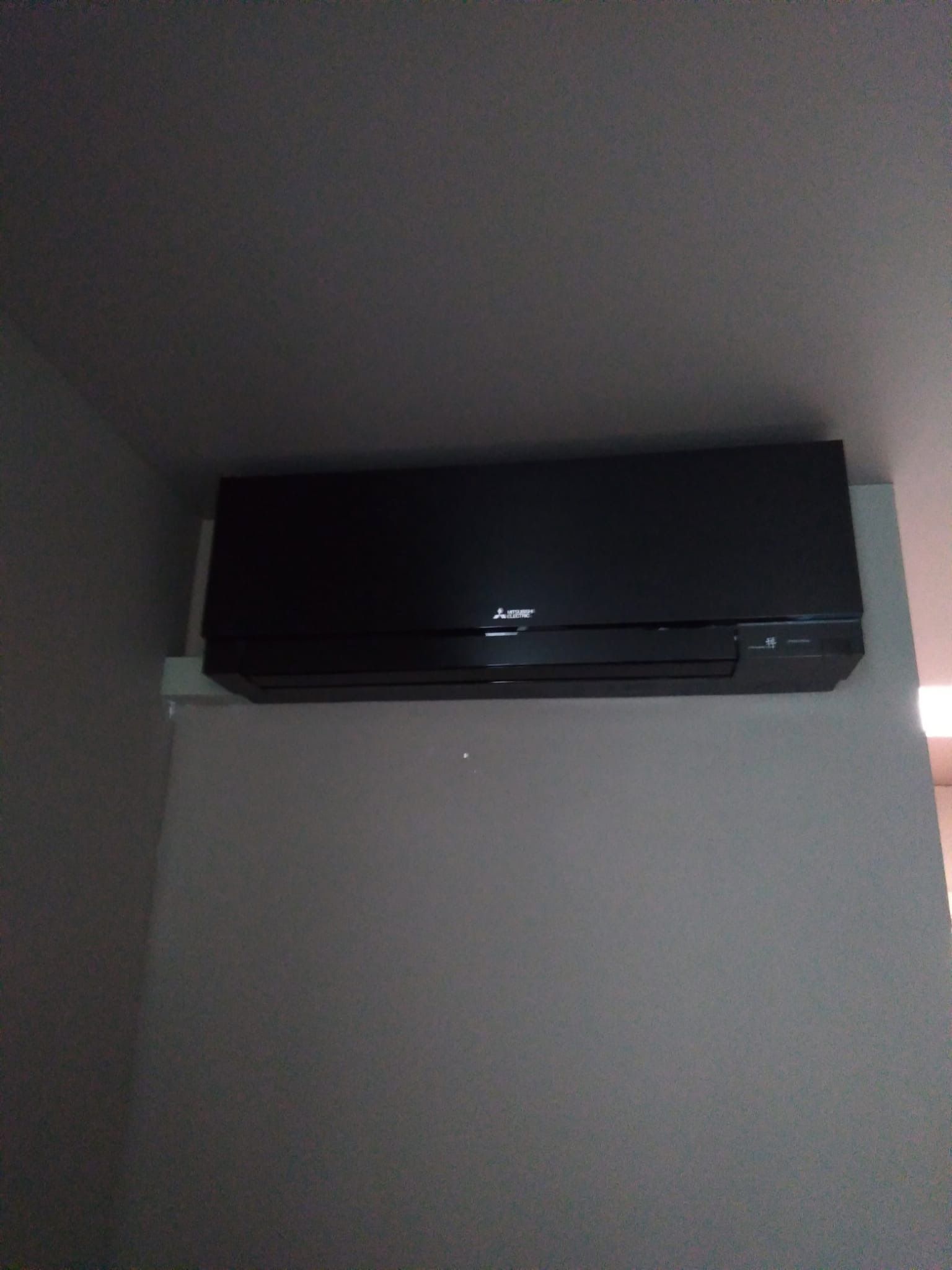 Condizionatore nero montato su una parete grigia.