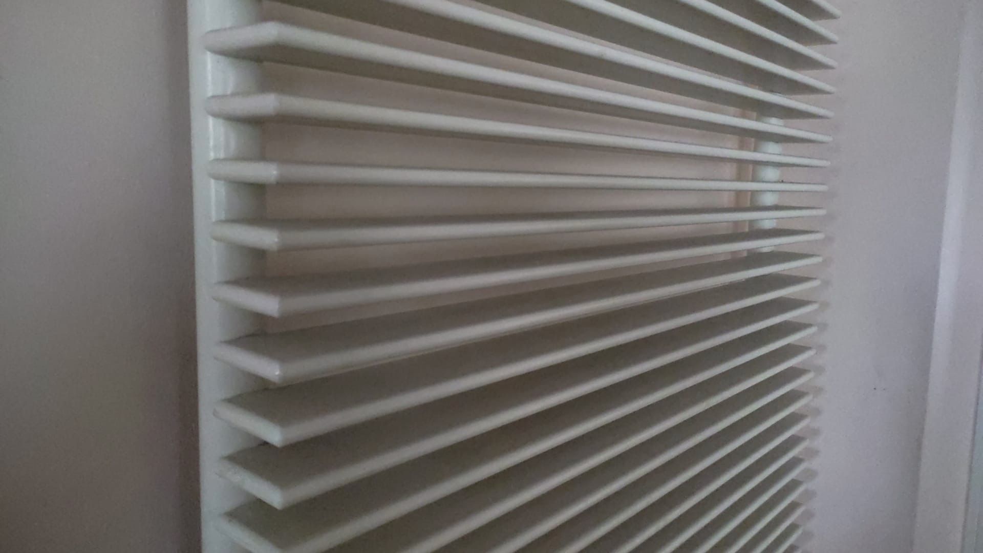 Radiatore orizzontale bianco montato su una parete bianca.