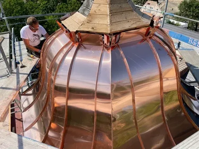 Auf einem Gebäude wird eine Kupferkuppel errichtet