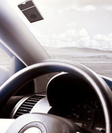 Interior del coche con volante y salpicadero, con vistas a una carretera iluminada y a la costa que se extiende ante nosotros.