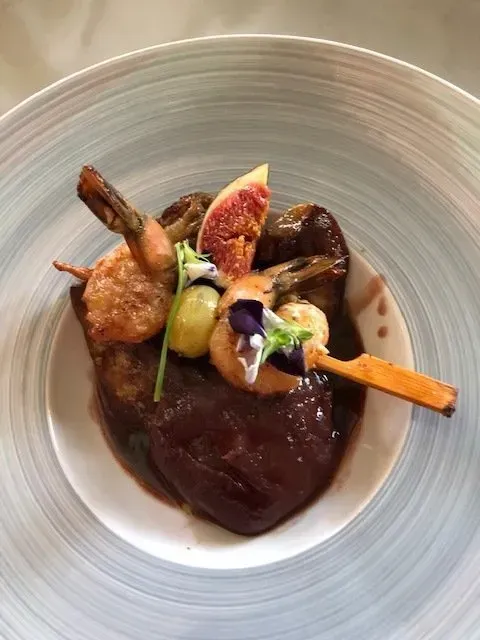 Brochette sur sauce dans une assiette blanche