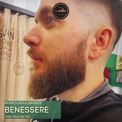 Uomo con barba e taglio di capelli sfumato in un barbiere.