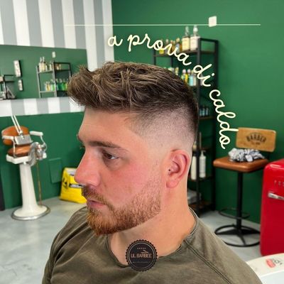 Persona con i capelli argentati in un barbiere. Primo piano. Parete verde e bianca, scaffale con prodotti.