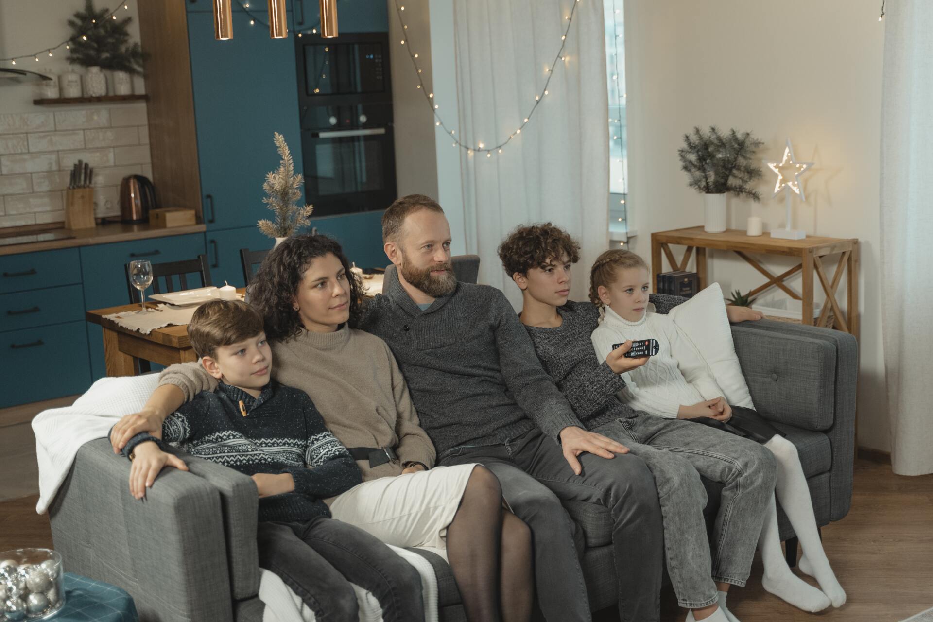 Une famille de 2 adultes et 3 enfants assis dans un canapé