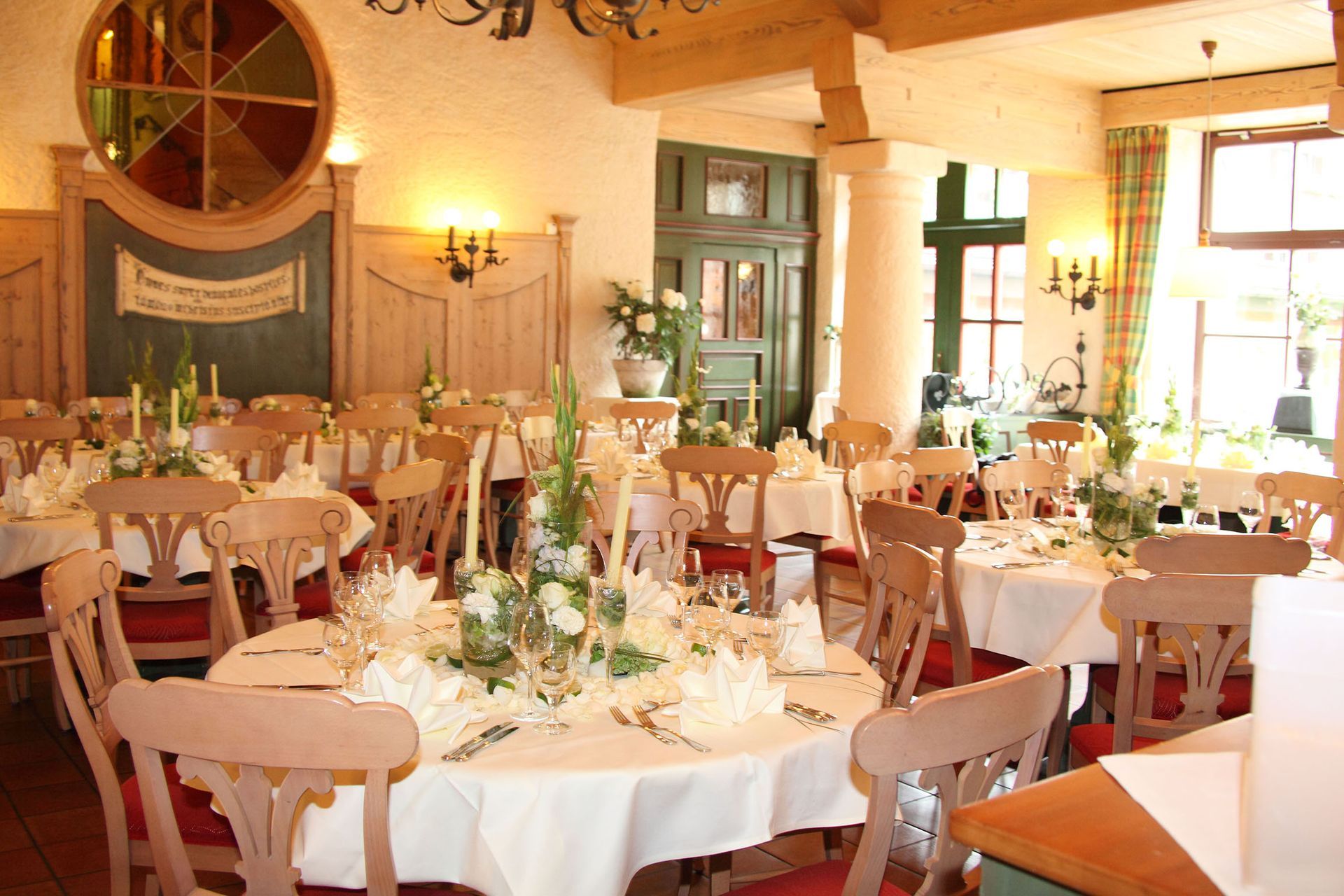 Festlich gedeckter Restaurantbereich mit runden Tischen und warmer Holz­einrichtung.