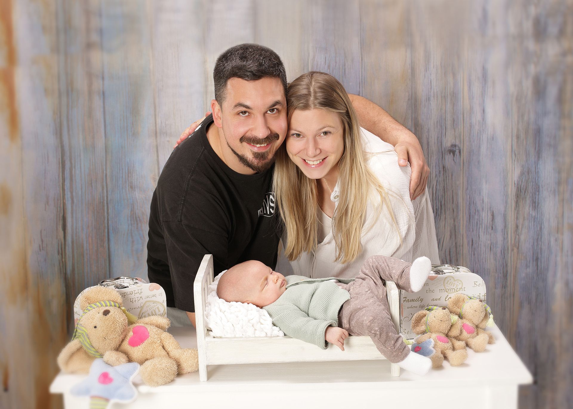 Familienfoto mit Vater und Tochter, die ein Neugeborenes liebevoll umrahmen.